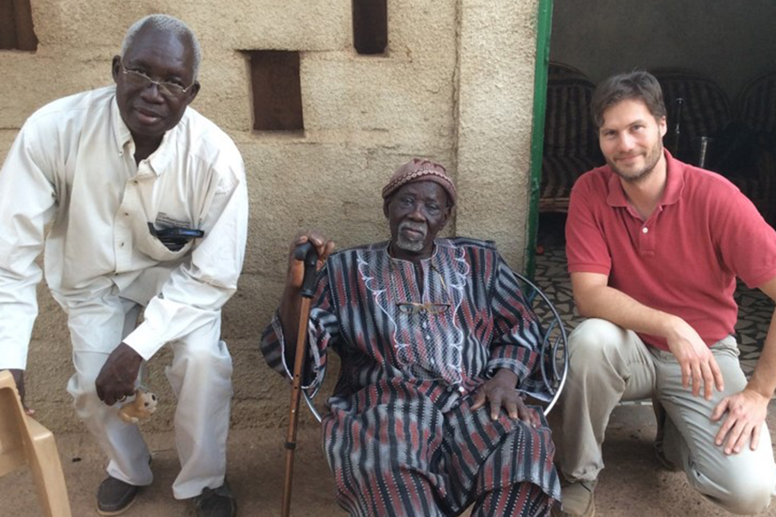 three men in Africa sitting next to cement wall